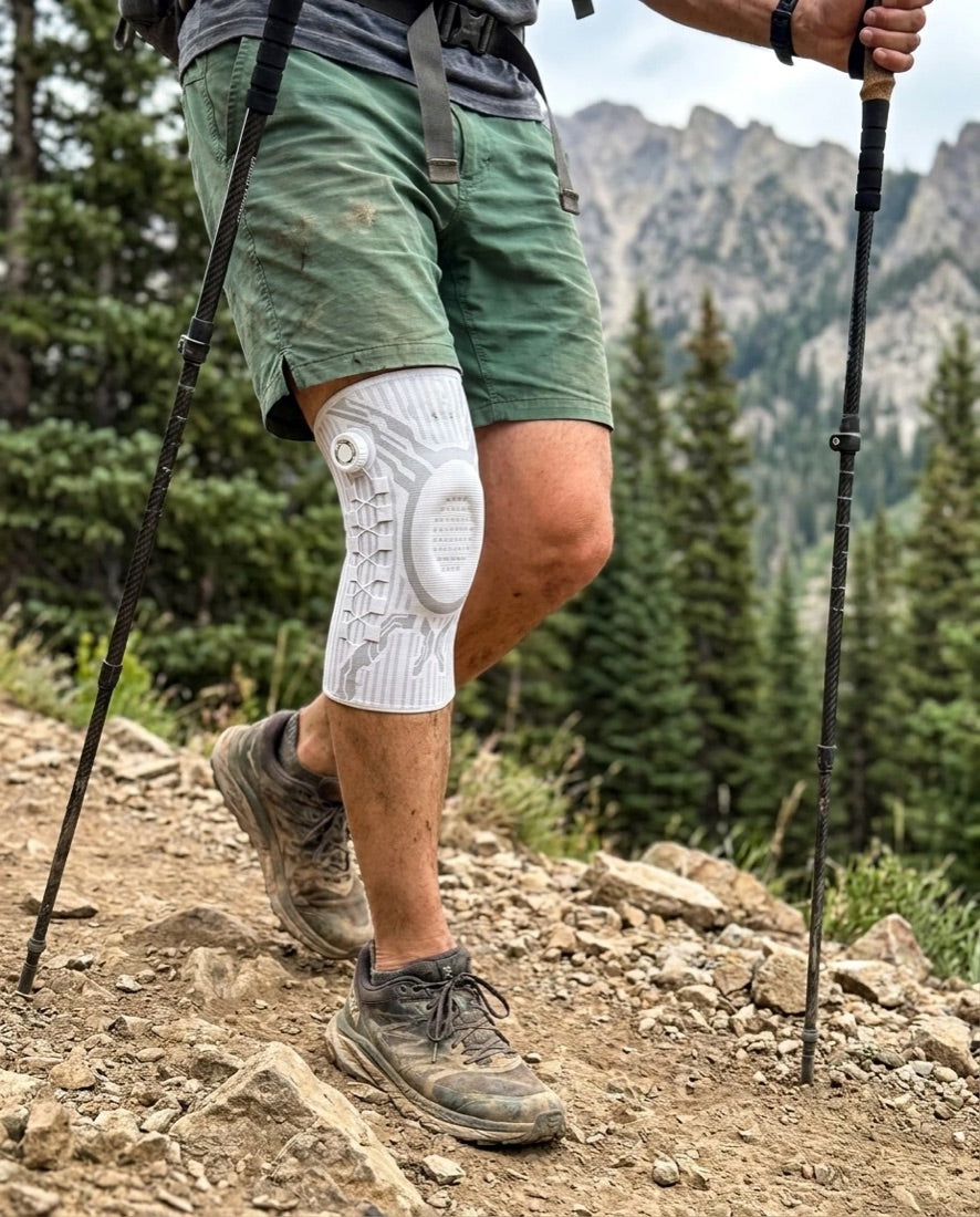 Hiker on a rocky mountain trail wearing a white Chipaki knee brace